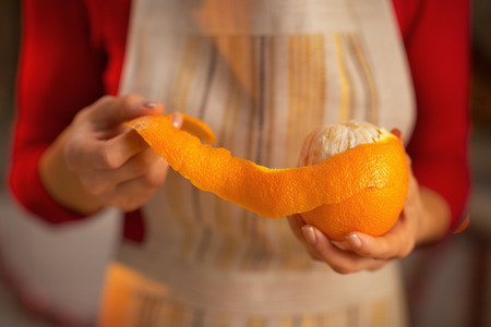 Closeup on young housewife removing orange peelの写真素材