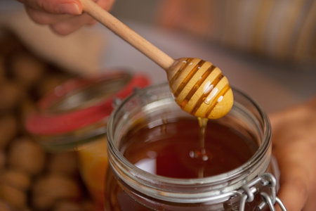 Closeup on honey flowing down from honey dipper in jarの写真素材