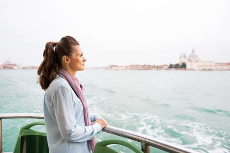 Young woman travel by vaporetto in venice, italy and looking on copy spaceの写真素材