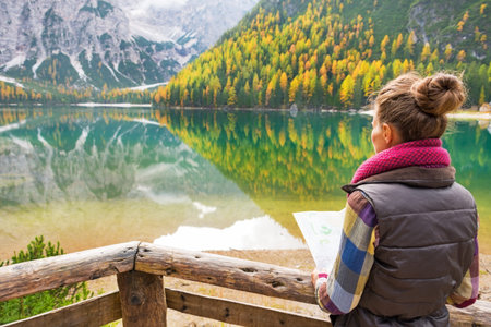 Young woman with map on lake braies in south tyrol, italy. rear view