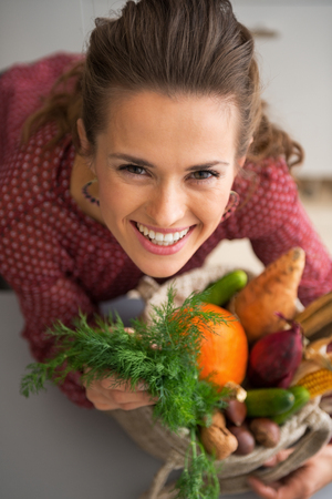 Portrait of happy young housewife with shopping bag of fresh vegetables from local marketの写真素材