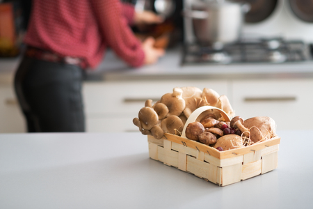 Closeup on basket with mushrooms on table and young housewifeの写真素材