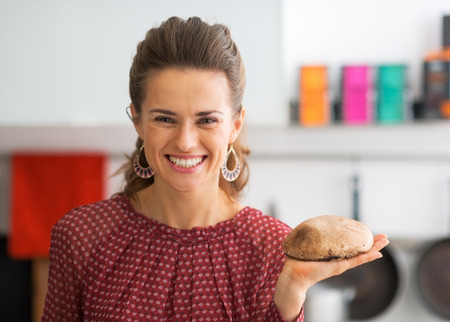 Portrait of happy young housewife showing mushroomの写真素材