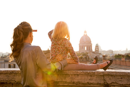Mother and baby girl looking on rome panorama on sunsetの写真素材