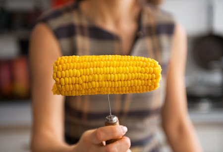 Closeup on young woman showing boiled cornの写真素材