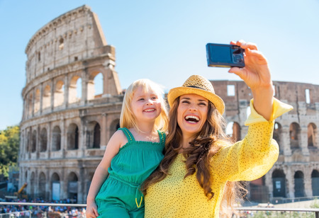 Happy mother and baby girl making selfie in front of colosseum in rome, italyの写真素材