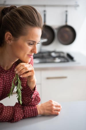 Young housewife with fresh rosmarinus in kitchenの写真素材
