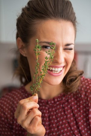 Portrait of happy young housewife showing fresh thymusの写真素材