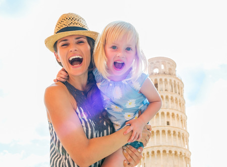Portrait of smiling mother and baby girl in front of leaning tower of pisa, tuscany, italyの写真素材