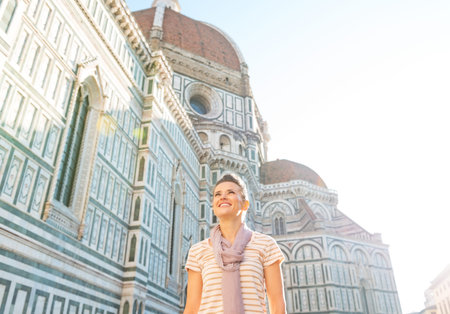 Happy young woman in front of cattedrale di santa maria del fiore in florence, italyの写真素材
