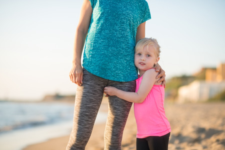 Baby girl hugging mother on beach in the eveningの写真素材
