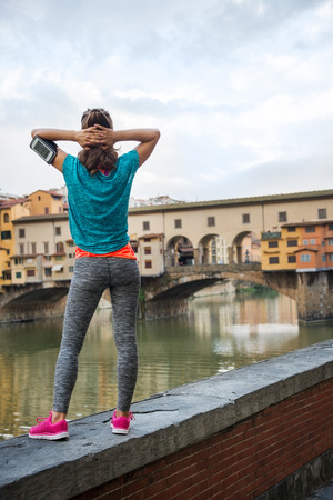 Fitness woman standing in front of ponte vecchio in florence, italy. rear viewの写真素材