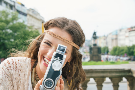 Joyful brunette hippy-looking woman tourist using vintage retro camera  on Wenceslas Square in Prague. Tourism travel concept.の写真素材