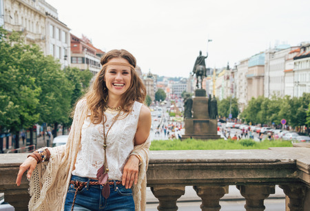 Happy longhaired hippy-looking woman tourist in knitted shawl and white blouse standing on Wenceslas Square, Prague. Tourism travel concept.の写真素材
