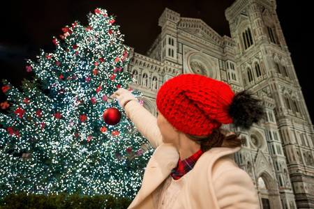 Woman pretend decorating Christmas tree near Duomo with Christmas ball. Evening. Christmas decorated historical area of Florence, Italyの写真素材