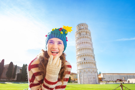 Young, itching from energy and searching for excitement. I'm going to Christmas trip to Italy. It is a no-brainer. Woman in Christmas tree hat thinking about something in front of Leaning Tour of Pisaの写真素材