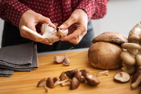 A woman's elegant hands are separating a head of garlic into individual cloves as she is preparing a fall meal. When these are mixed with mushrooms, the earthy smell of autumn will fill the air.の写真素材
