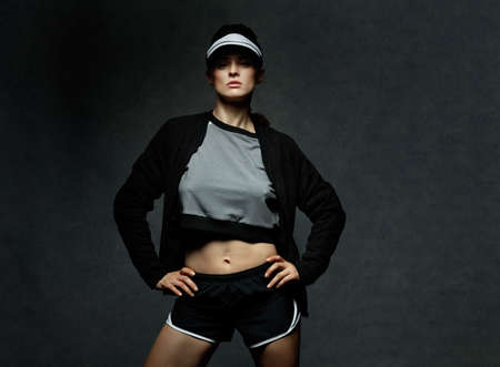 Boutique fitness studio style. Young woman athlete posing against dark backgroundの写真素材