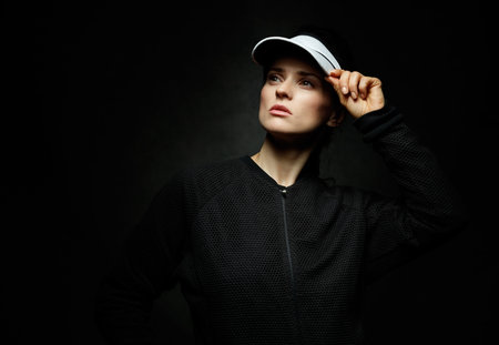 Boutique fitness studio style. Portrait of young fit woman looking aside against black backgroundの写真素材