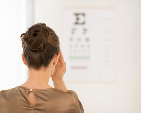 Modern health care. Seen from behind woman testing vision with Snellen chart