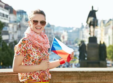 Catch the spirit of old Europe in Prague. Smiling young woman in sunglasses showing Czech flag near National Museum at Wenceslas Squareの写真素材