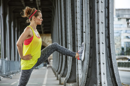 Outdoors fitness in Paris. young woman jogger stretching on Pont de Bir-Hakeim bridge in Paris