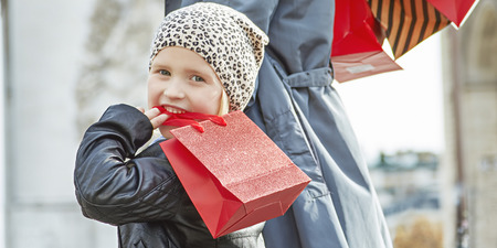 Stylish autumn in Paris. smiling young mother and child with shopping bags near Arc de Triomphe in Paris, France walkingの写真素材