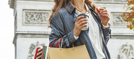 Stylish autumn in Paris. young fashion-monger in trench coat in Paris, France with shopping bags having coffee and macaroonの写真素材