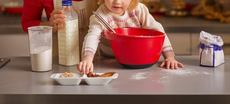 Baby helping mother make christmas cookies in christmas decorated kitchen