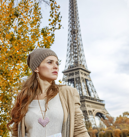 Autumn getaways in Paris. young tourist woman on embankment in Paris, France with map looking into the distanceの写真素材
