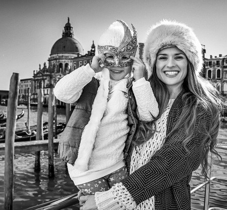 Another world vacation. Portrait of smiling modern mother and child tourists in Venice, Italy wearing Venetian maskの写真素材