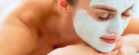 Relaxed young woman with revitalising mask on face laying on massage tableの写真素材