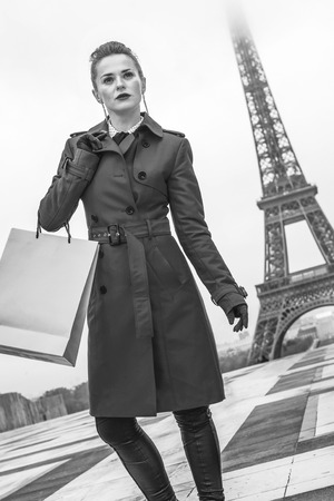 Bright in Paris. stylish woman in red trench coat in Paris, France with shopping bag looking into the distanceの写真素材