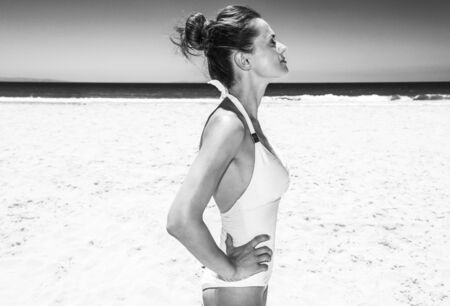 Heading to white sand blue sea paradise. Relaxed woman in white swimsuit at sandy beach on a sunny dayの写真素材