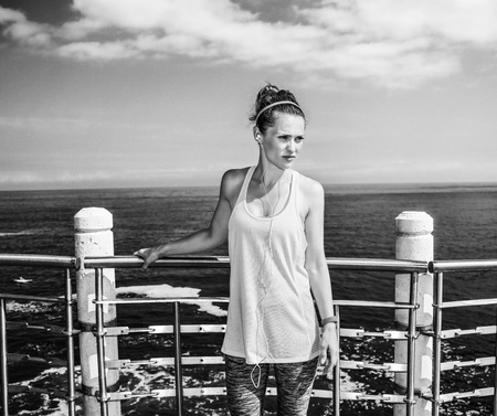 Look Good, Feel great! young healthy woman in fitness outfit looking aside and standing at the embankmentの写真素材