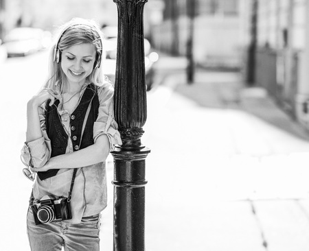 Happy hipster girl listening music on city streetの写真素材