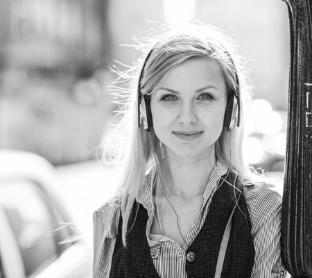 Portrait of happy girl listening music on city streetの写真素材
