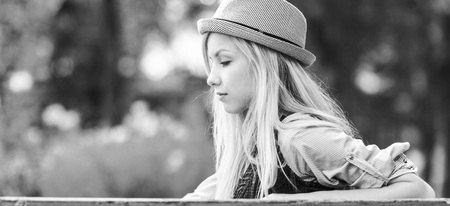 Thoughtful hipster girl sitting on bench in the parkの写真素材
