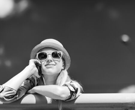Happy hipster girl talking mobile phone on city streetの写真素材