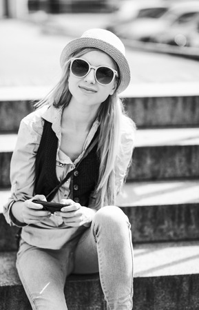 Portrait of young hipster sitting on bench in the cityの写真素材