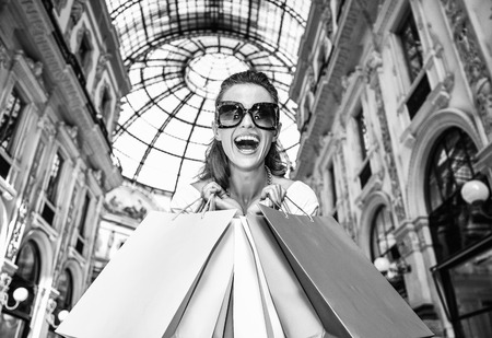 Discover most unexpected trends in Milan. Portrait of smiling fashion monger in eyeglasses with colorful shopping bags in Galleria Vittorio Emanuele IIの写真素材