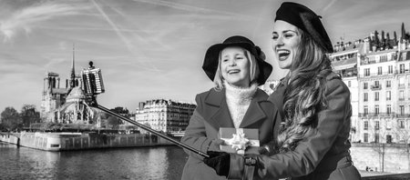 Bright in Paris. trendy mother and child travellers in red coats on embankment in Paris, France with...