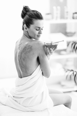 Young woman sitting on massage table with honey plateの写真素材