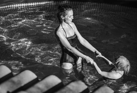 Fun weekend alfresco. happy active mother and daughter in swimsuit in the swimming pool playingの写真素材