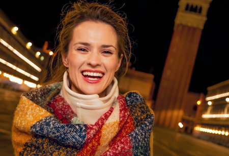 Classical tourist enjoyment in Venice, Italy.  Portrait of smiling elegant woman wrapped in a long scarf at San Marco square in Venice, Italy in the winter standing near St Mark's Campanileの写真素材