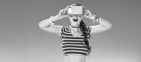 Perfect summer. smiling active woman on the seacoast wearing cardboard VR gearの写真素材