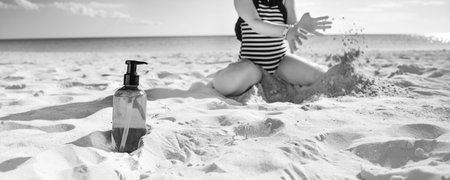 Sun kissed beauty. Closeup on sunscreen bottle and child playing in background in swimwear on the...