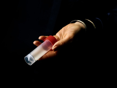 Black Mania. woman hand isolated on black showing sample jarの写真素材