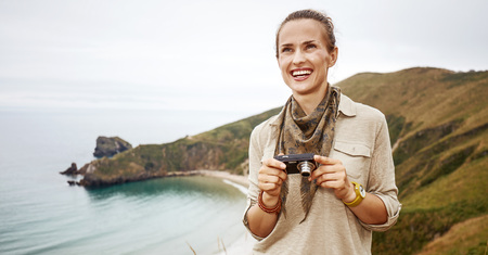 Into the wild in Spain. adventure woman hiker with digital camera looking into distance in front of ocean view landscapeの写真素材