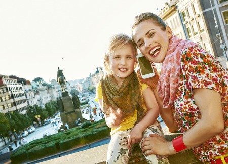 The spirit of old Europe in Prague. smiling modern mother and daughter travellers in Prague, Czech Republic speaking on a smartphoneの写真素材